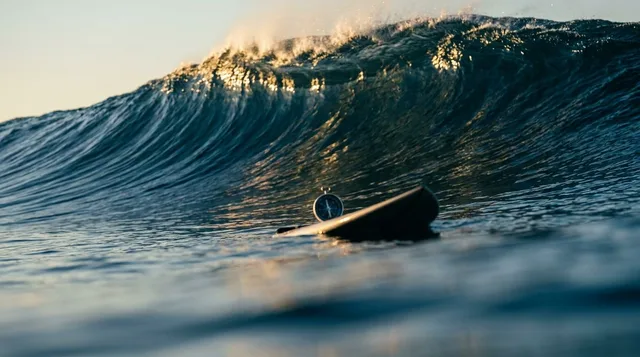 A massive wave of water beginning to form and swell in the ocean, with a lone surfer paddling into position just ahead of it — perfectly timed before the wave reaches full force. The image captures the critical moment of early positioning, with calm water in the foreground transitioning into powerful momentum behind. The contrast between stillness and explosive energy visually communicates the concept of identifying buying momentum before the crowd arrives.