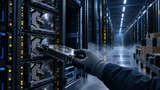 A dim data-center aisle with server racks of hard disk drives; a technician installs a new drive while nearby crates suggest incoming expanded storage capacity.