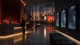 A modern media company interior split between a warmly lit lobby and a wall of dim, underperforming digital advertising screens, with a production stage visible in the background.