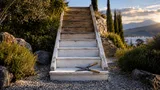 A single staircase rendered in two tones of weathered wood sits center-frame outdoors, its lower steps painted bright white and fading to bare, unpainted wood near the top—visually suggesting a capped, defined climb rather than an open-ende